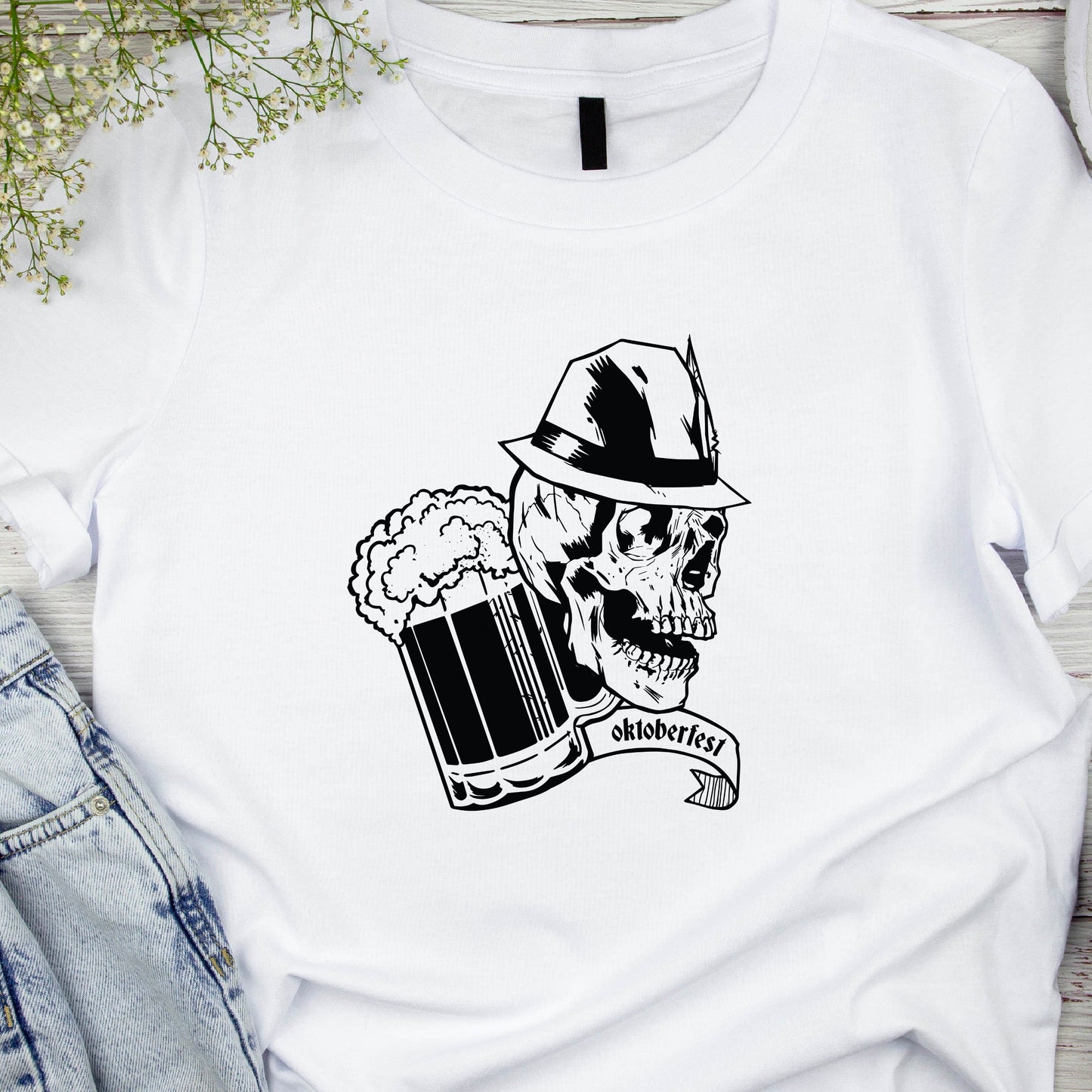 White t-shirt with a skull and beer mug graphic on a wooden surface with denim jeans and headphones.