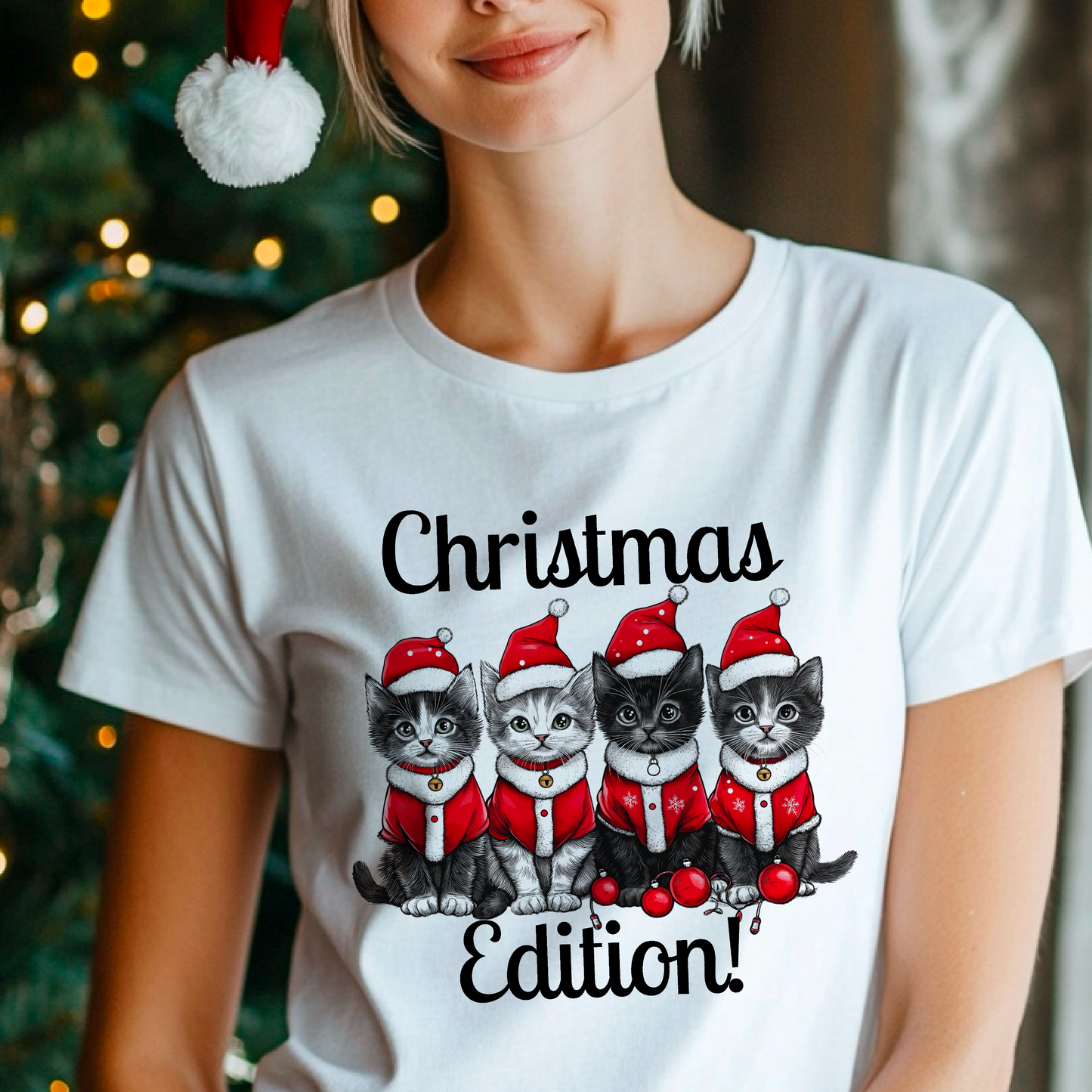 A person wearing a white t-shirt with a graphic print of three cartoon cats in Santa hats and the text 'Christmas Edition!'