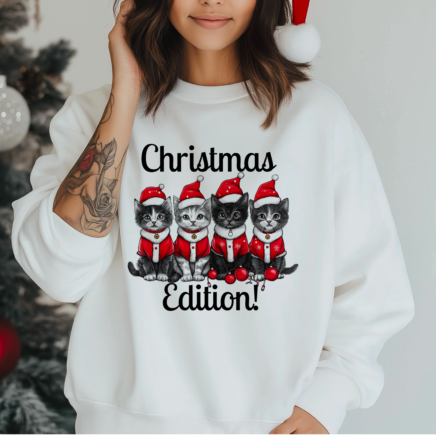 A person wearing a white sweatshirt with a festive Christmas edition cat-themed design, featuring multiple cartoon cats dressed in Santa hats.