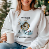 A woman sitting wearing a white crewneck sweatshirt with a Christmas-themed design, including a melted clock and text 'It’s time to celebrate'.