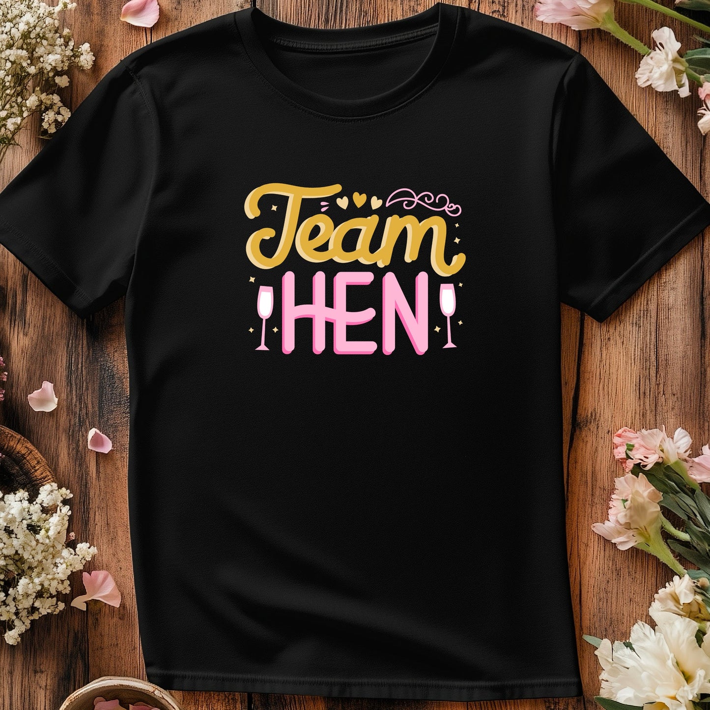 Black t-shirt with 'Team Hen' text on a wooden surface with flowers