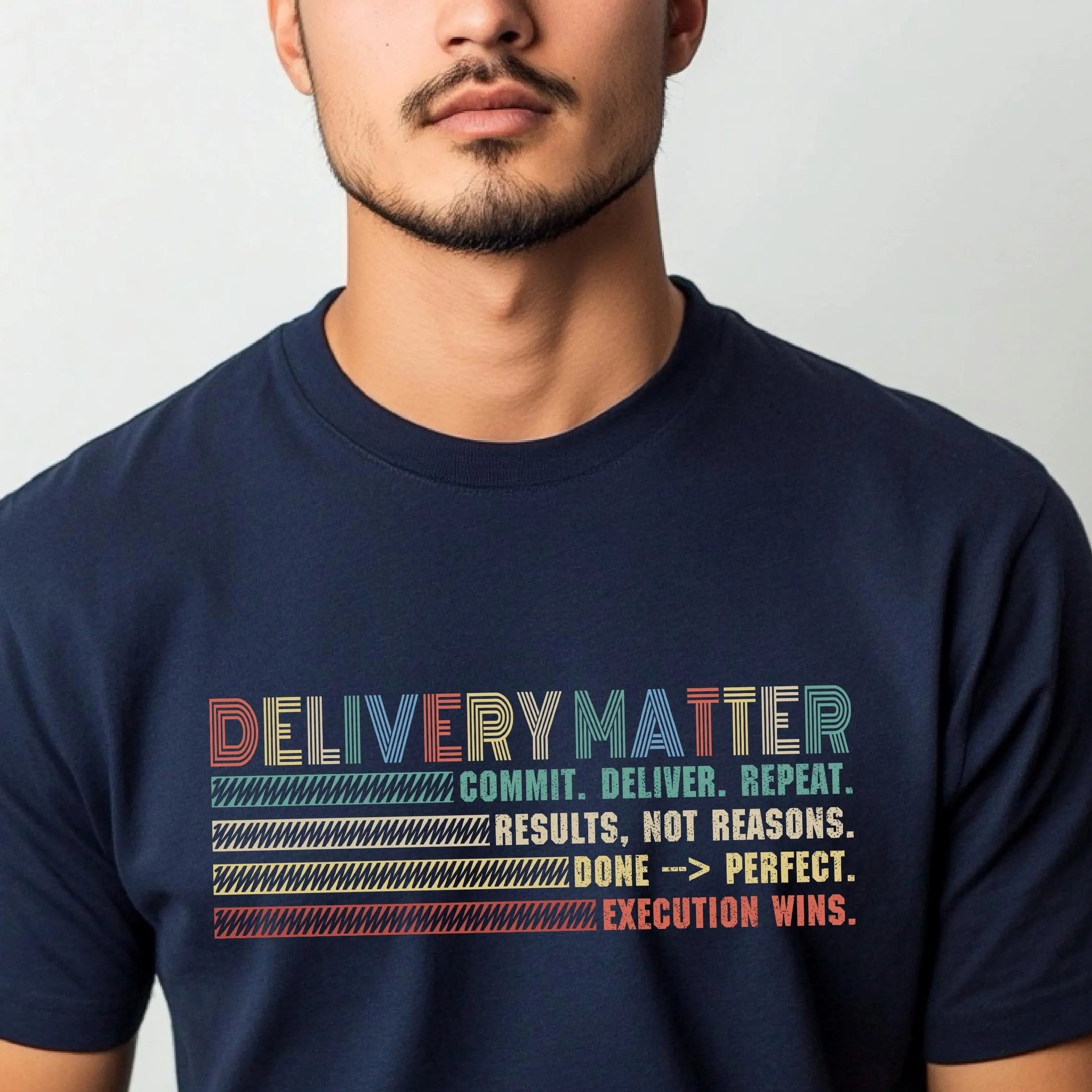 Man wearing a navy blue t-shirt with motivational text design on a plain background