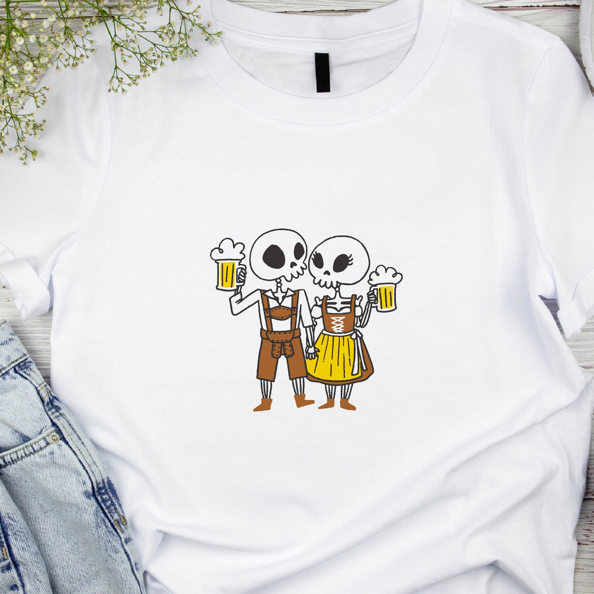White t-shirt with cartoon skeletons holding beer mugs on a wooden surface.